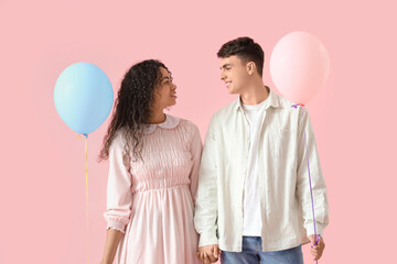 Young couple in love with balloons on pink background