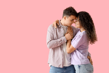 Young couple in love hugging on pink background