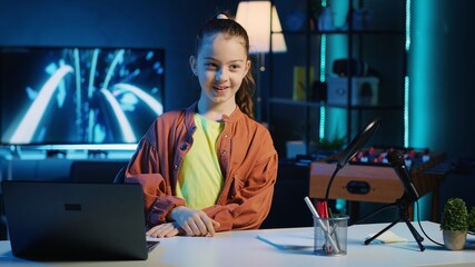 Kid content creator using recording devices to shoot intro for family vlog channel on online platforms. Cute child internet star warmly welcoming dedicated gen Z viewers, filming in home studio
