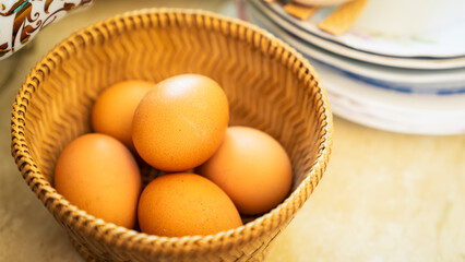 Several eggs are in a wooden bowl on the kitchen table
