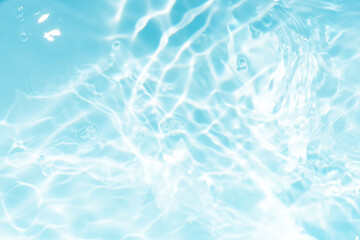 Blue water with ripples on the surface. Defocus blurred transparent blue colored clear calm water surface texture with splashes and bubbles. Water waves with shining pattern texture background.