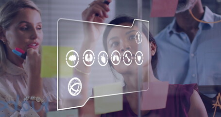 Image of multiple digital icons against diverse colleagues discussing over memo notes at office