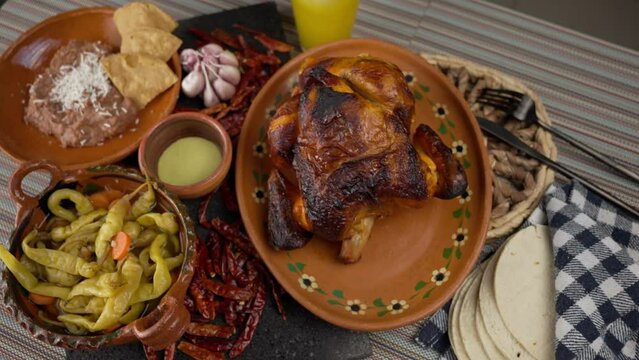 an overhead view of a roast chicken on a clay plate, festive food