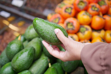 young woman hand holding avocado shopping at retail store 