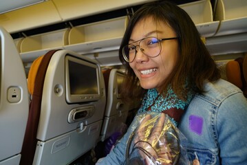 asian women sitting and smiling on the airplane seat in the plane