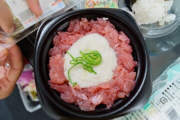 minced raw tuna on rice in black plastic bowl