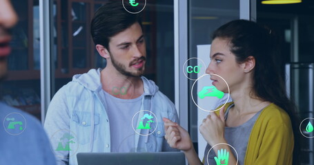 Image of multiple icon in circles over caucasian coworkers discussing reports on laptop