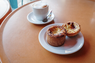 Close-up of two Portuguese custard tarts, also known as Pastéis de Nata, served on a white plate.