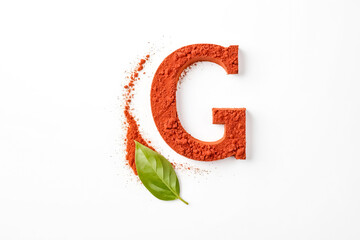 Fototapeta premium Letter G made of red powder with green leaf