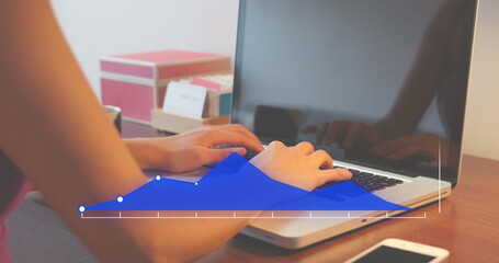 Image of graph over midsection of biracial woman typing on keyboard of laptop in office