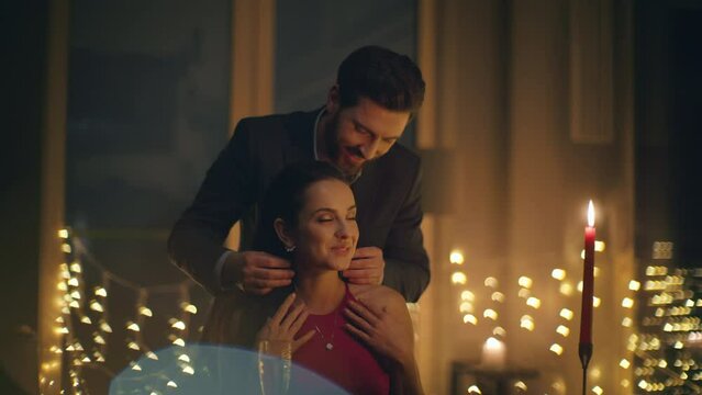 Handsome man bringing necklace to woman at romantic dinner with candles closeup