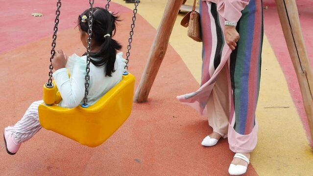  child having fun on a swing on the playground in public park.