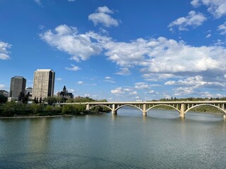 Naklejka premium Puente sobre río y ciudad de fondo con cielo azul y algunas nubes. 