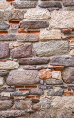 Historic stone wall. rough, old and worn ancient surface. big rock pieces.
