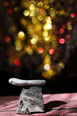 Empty stone podium and golden flare bokeh lights on black background, blurred fireworks.  Celebration and holidays.  Background for design. Space for pesentation product