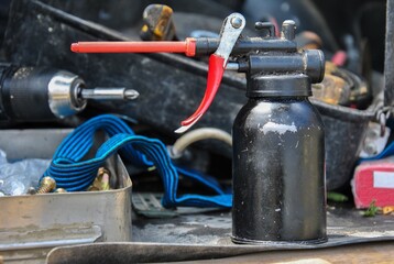 oil can on a workbench in a workshop close-up. blurred background. black oiler