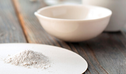 Small ceramic mortar, bowl and pestle with white powder on wooden background