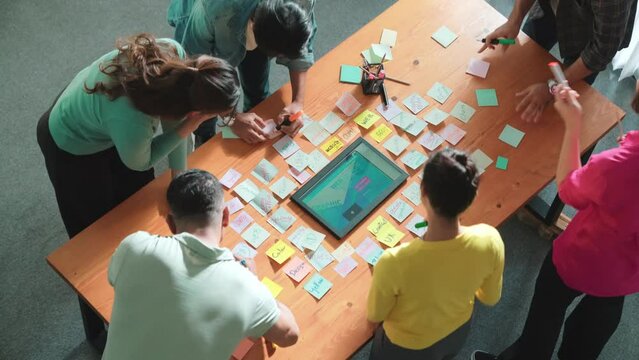 Top view of skilled programmer brainstorming idea about mobile phone interface while develop app development by using wireframe prototype. Web designer planning at table with sticky notes. Symposium.