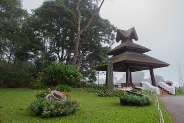 A living pavilion with a roof and brown pillars in the garden, photographed in the morning and mist