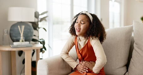 Young girl, stomach ache or allergies on couch in home for health problem or digestion recovery on...