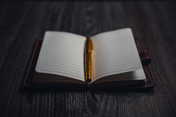 A notebook with a gold pen on the table in the candlelight