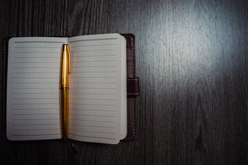 A notebook with a gold pen on the table in the candlelight