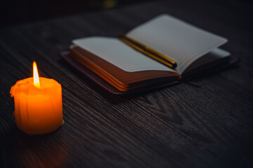 A notebook with a gold pen on the table in the candlelight