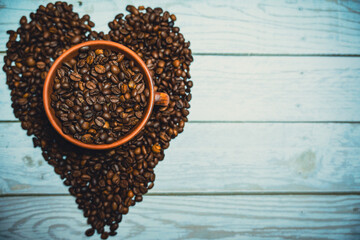 Coffee beans in a clay mug. A heart made of coffee beans