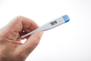 A man's hand holds an electronic thermometer on a green background