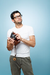 Thinking, man and photographer with camera in studio for picture, creative media and memory as artistic reporter. Male paparazzi, idea and vintage digital tech for production film on blue background