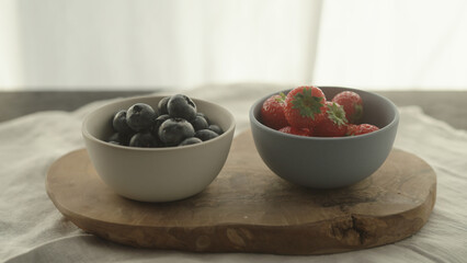 fresh blueberries and strawberries in ceramic bowls with natural light
