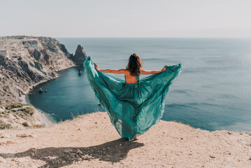 Woman green dress sea. Female dancer posing on a rocky outcrop high above the sea. Girl on the...