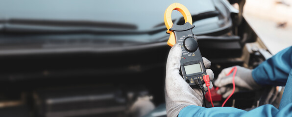 Close-up hand auto mechanic using meter to check car battery fail problem for service or change...