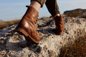 Brown boots standing strong on top of rock in vast field adventure and exploration in nature