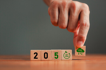 Net zero emmissions concept with Hand puts wooden cubes with CO2 reducing icon and 2050 number for...