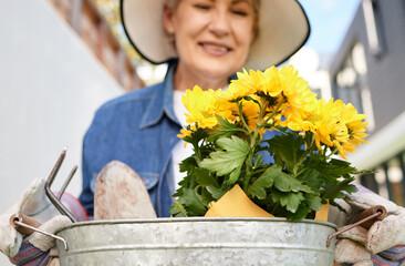 Senior woman, plants and container in outdoor for happiness, planting floral for earth day. Female person, gardening or flowers in bucket for relaxed retirement, smile in backyard for wellness © peopleimages.com