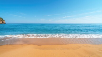 Naklejka premium A serene beach with golden sand meeting the calm blue sea under a clear sky, ideal for vacation and travel visuals.