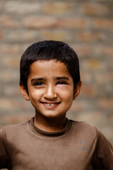 Portrait of a poor staring hungry orphan boy in a refugee camp with a laughing expression on his face