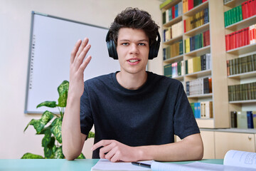 Web cam portrait of college student guy in headphones looking talking to camera