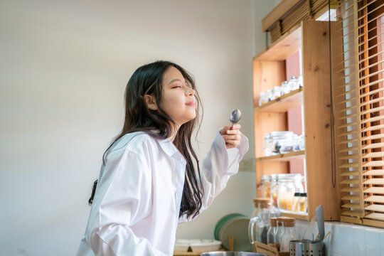 Asian young woman cooking  and smelling tasting fresh delicious from soup pot