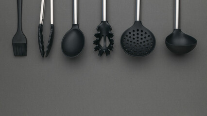 Assorted Black Kitchen Utensils on Gray Background - Spoon, Ladle, Tongs, Brush, Strainer, Pasta...