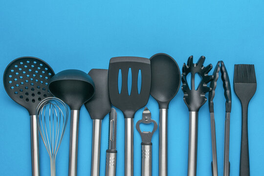 Assorted Kitchen Utensils with Stainless Steel Handles on a Blue Background