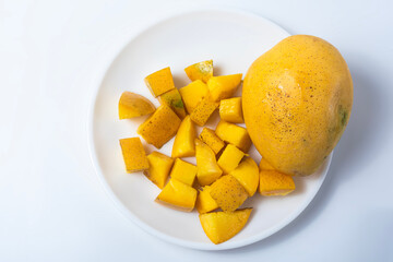 Top view of fresh ripe mango and sliced mango on white plate. Healthy food concept. Closeup