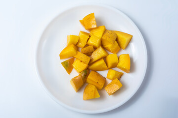 Ripe delicious mango slices on white plate isolated on white background.