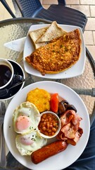 Traditional Big breakfast with fried eggs, sausages, bacon, bean, French toast, bread and black coffee.