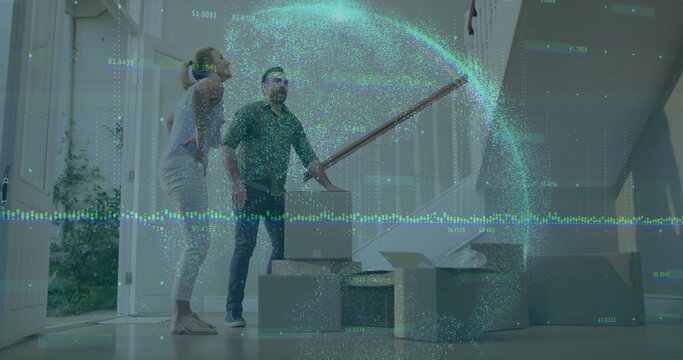 Image of graphs and globe, caucasian couple picking up cardboard box and keeping it on floor - Powered by Adobe