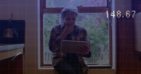 Image of graph and changing numbers over biracial senior woman using digital tablet