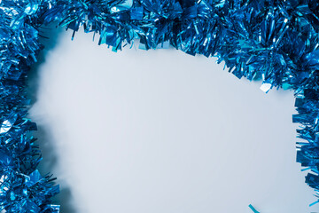 Blue tinsel on a white background with copy space for text.