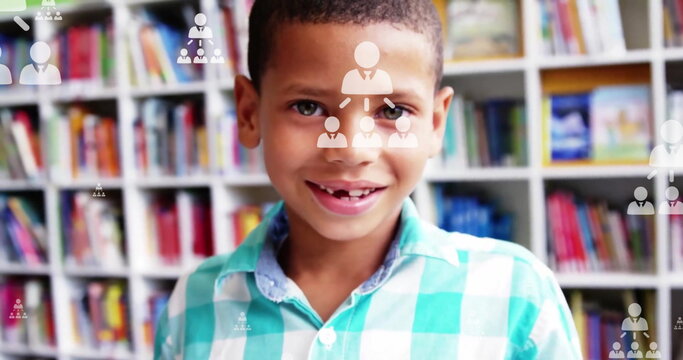 Image of profile icons flowcharts over close up of smiling biracial boy standing in library - Powered by Adobe