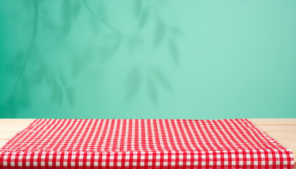 Empty wooden deck table and red checked tablecloth over mint wallpaper background